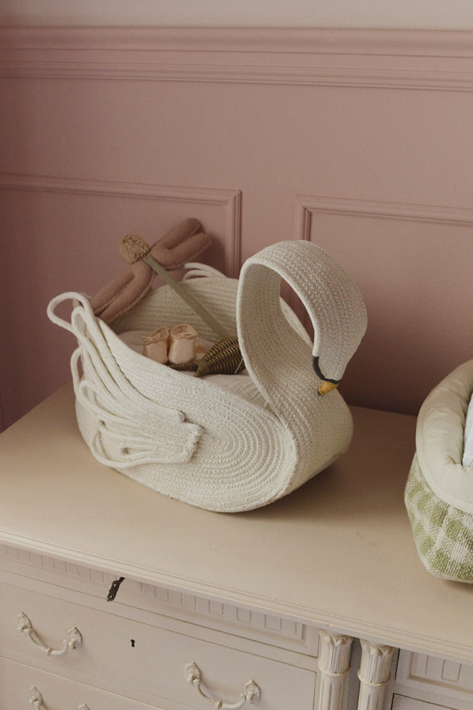 Cesta Swan sobre una cómoda, con una muñeca y pequeños objetos guardados en su interior.
