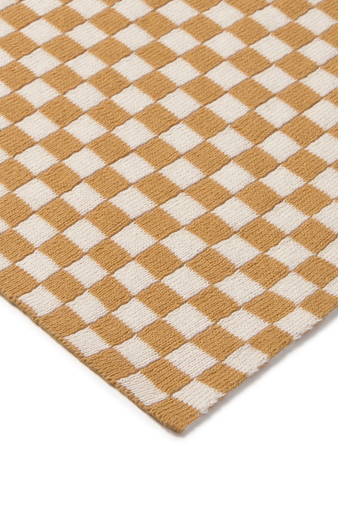 Detalle de la esquina de la manta Tiles en miel y natural.