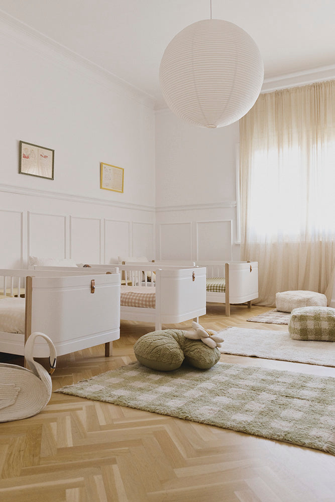 Alfombra Vichy matcha en una habitación infantil luminosa con cuna blanca.