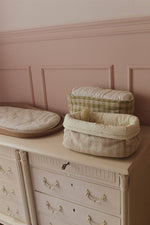 Cestas acolchadas rosa y matcha sobre una cómoda en una habitación de paredes rosas.