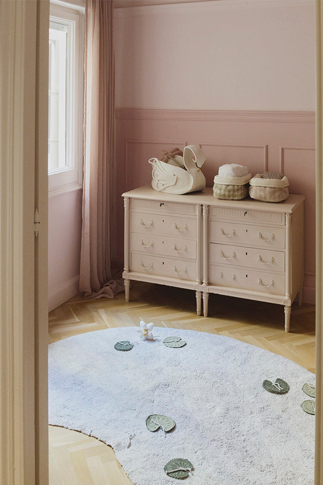 Habitación infantil con una cómoda decorada con cestas acolchadas y una alfombra Swan Lake.