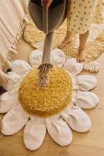 Niña jugando con una regadera de tela sobre el cojín White Daisy, colocado en el suelo.