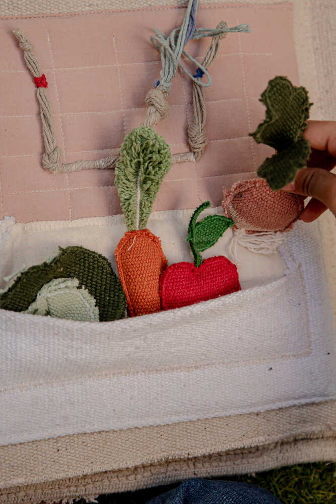 Página del libro sensorial con un fregadero de tela y verduras extraíbles en su bolsillo.